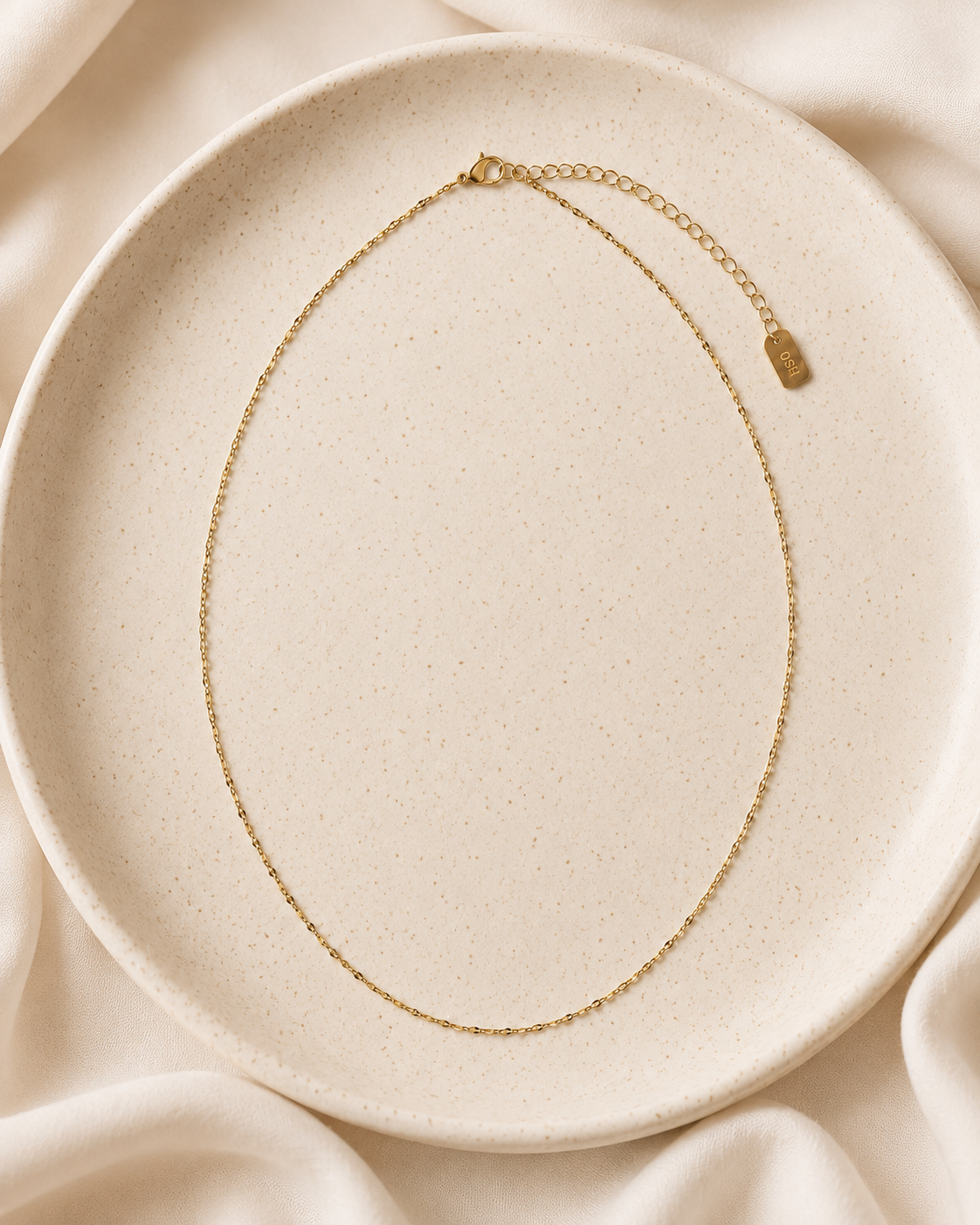 Soft Glow Necklace styled in a ceramic dish on soft ivory fabric.