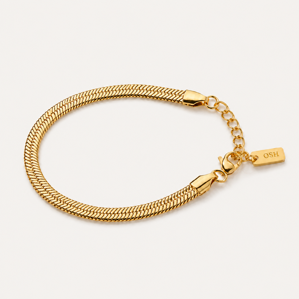 Gold bracelet with a clasp on a light beige background