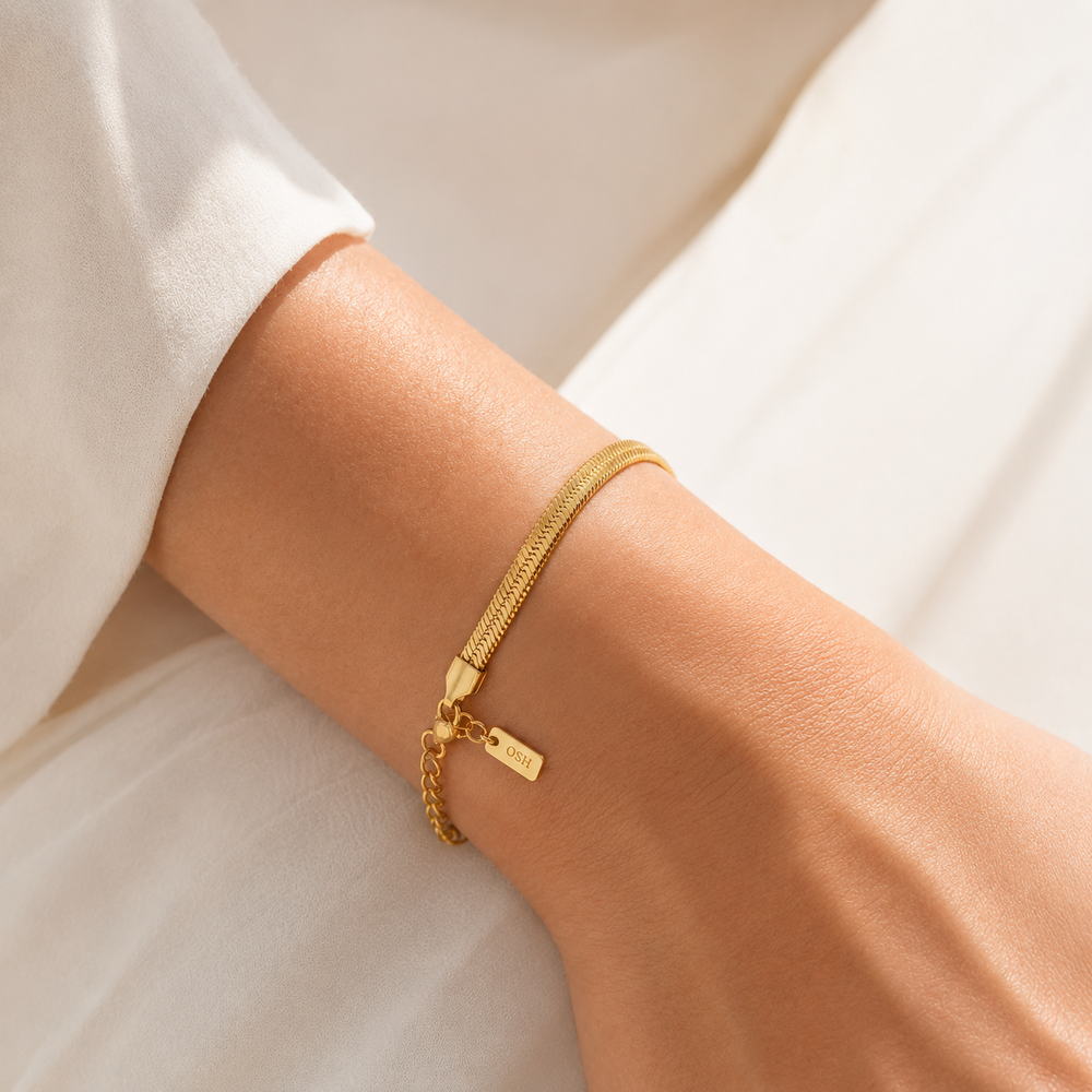 Gold bracelet on a person's wrist with a neutral background