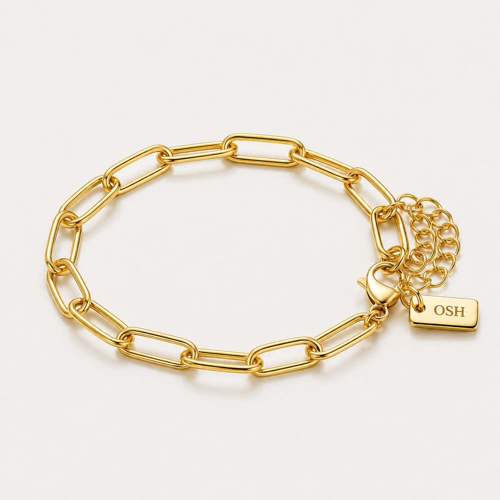 Gold chain bracelet with a lock charm on a light grey background