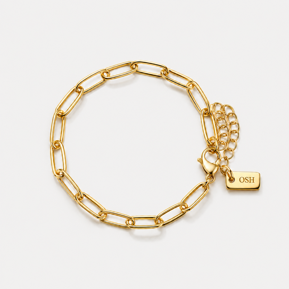Gold chain bracelet with a tag on a light grey background