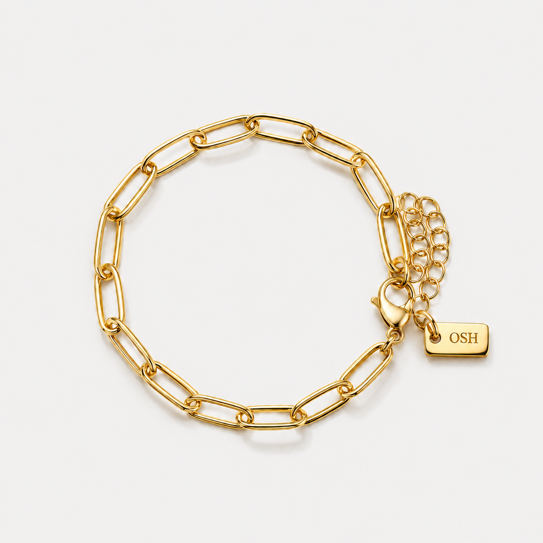 Gold chain bracelet with a tag on a light grey background