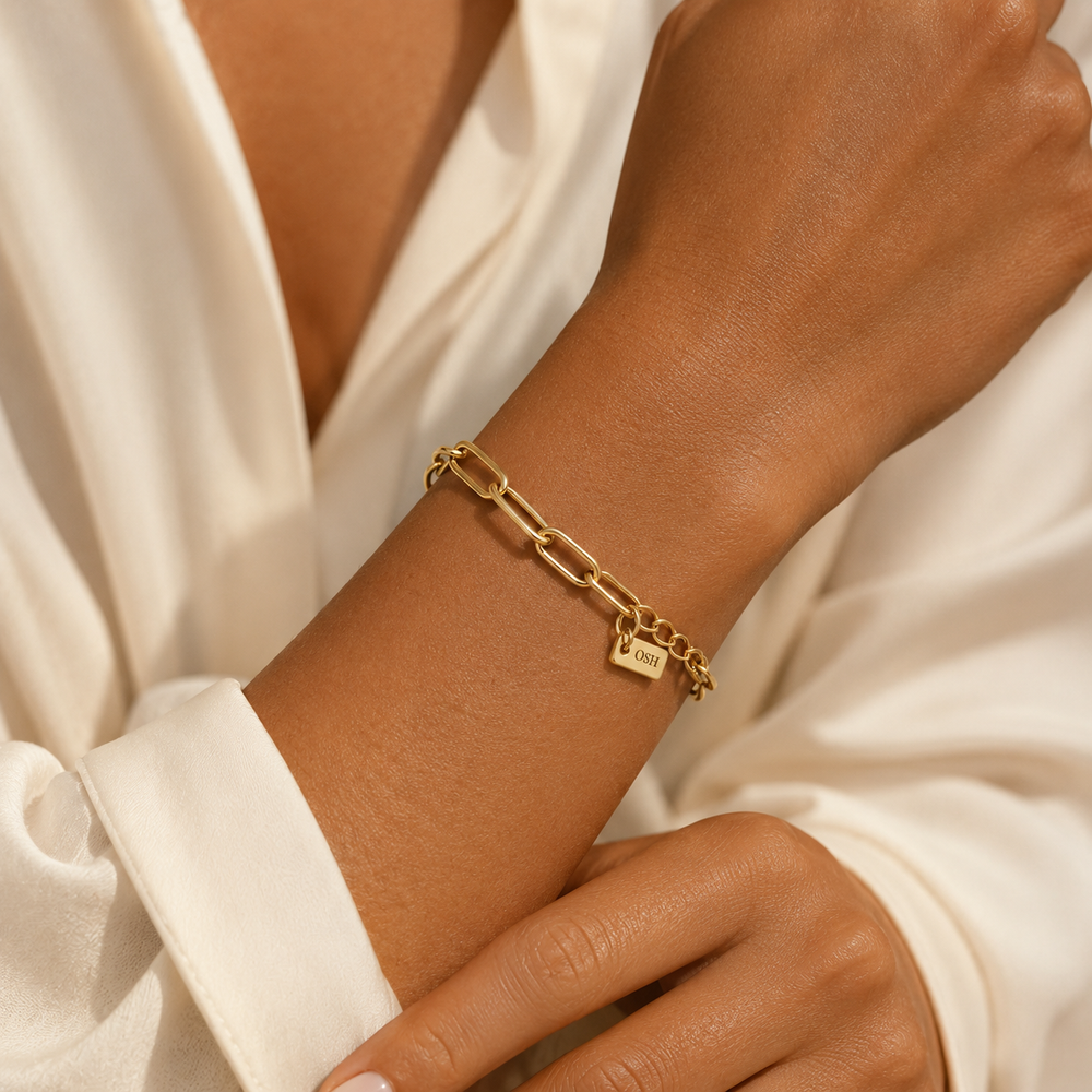 Gold chain bracelet on a wrist with a white shirt background