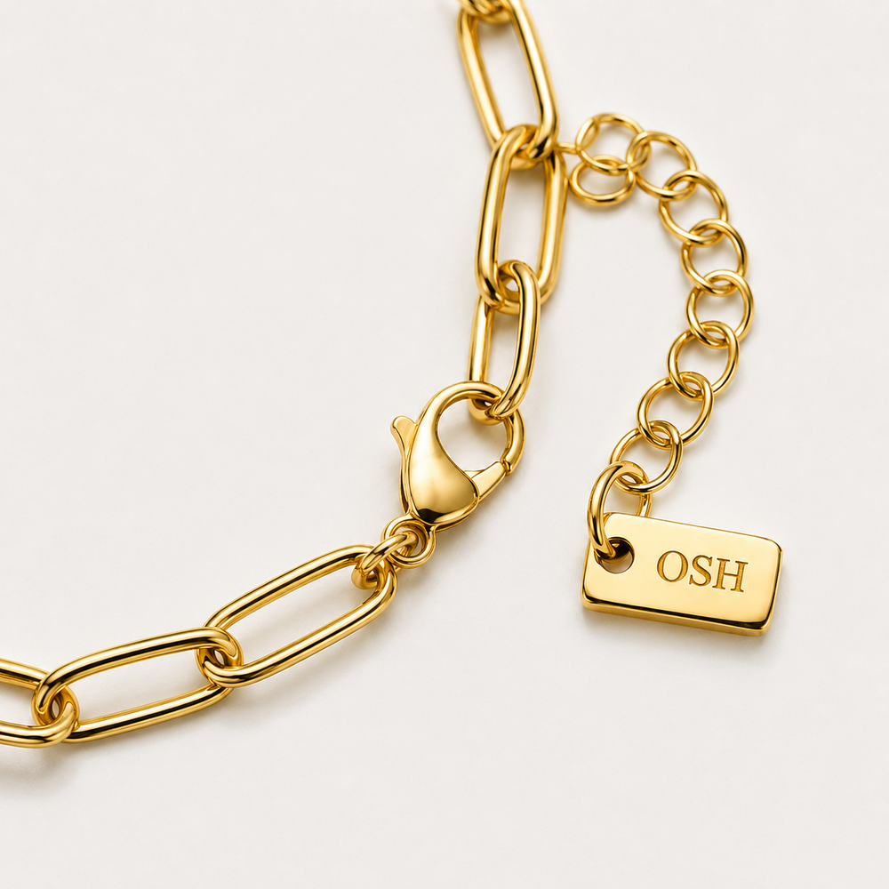 Gold chain bracelet with a tag on a light background
